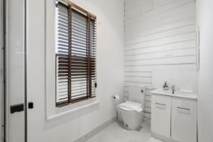 a white bathroom with a toilet and a window at Charming Sandy Bay Stay in Sandy Bay