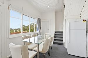 a dining room with a table and chairs and a refrigerator at Charming Sandy Bay Stay in Sandy Bay +5 photos