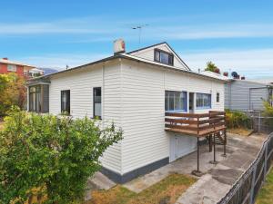 a small white house with a wooden deck at Charming Sandy Bay Stay in Sandy Bay