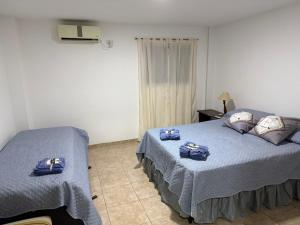 two beds in a bedroom with blue sheets and pillows at Edificio LUMARO in San Fernando del Valle de Catamarca +3 photos