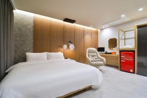 a bedroom with a large white bed and a chair at 통영 하운드호텔 죽림점 in Naejuk-to