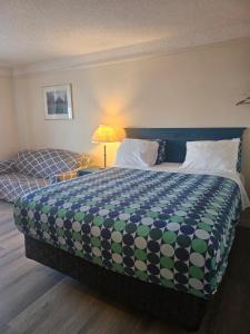 a hotel room with a large bed and a lamp at Moosomin Country Squire Inn in Moosomin +11 photos