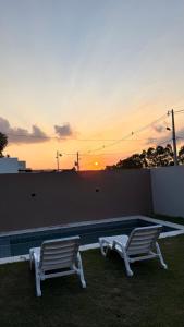 two chairs sitting next to a swimming pool at sunset at La casita de Ivanna in San Bernardino