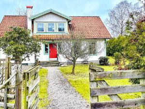 a white house with a red door and a fence at 4 star holiday home in ONSALA-By Traum in Onsala