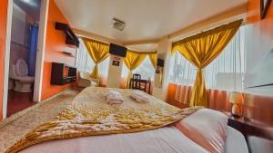 a bedroom with a large bed with yellow curtains at Hostal La Rosa Otavalo in Otavalo