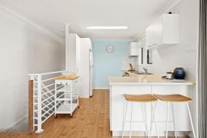 a kitchen with white cabinets and a kitchen island with stools at At The Beach in Lennox Head