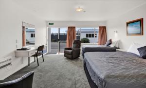 a hotel room with two beds and a desk at Avon Motel in Hawera
