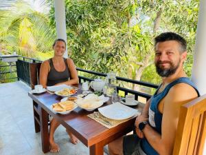 a man and a woman sitting at a table with food at Turtle Moon Lodge in Rekawa +19 photos