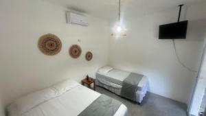 a white room with a bed and a television at Chalé Begê in Barra Grande