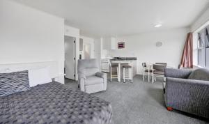 a bedroom with a bed and chairs and a kitchen at Avon Motel in Hawera +20 photos