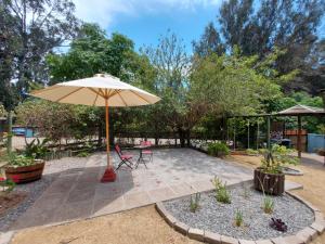 a patio with an umbrella and a table and chairs at Cabañas Alquymia in Algarrobo