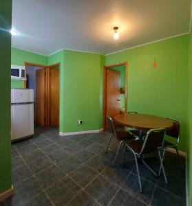 a kitchen with a table and chairs and green walls at Cabañas Alquymia in Algarrobo