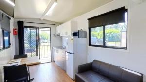 a living room with a couch and a refrigerator at Camden Holiday Park in Camden