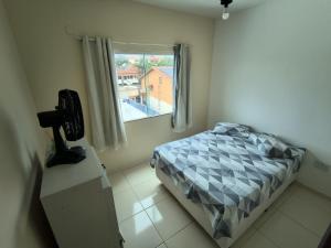 a small bedroom with a bed and a window at Casa e Mar Apto aconchegante perto da praia com estacionamento in São Pedro da Aldeia