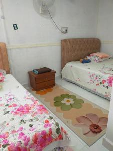a bedroom with two beds with flowers on the floor at IdaSari Guest House Bukit Bunga in Kampong Bukit Bunga