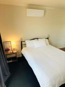 a bedroom with a white bed and a night stand at Logies Lodge in Ruakaka