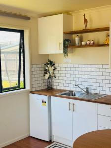 a kitchen with white cabinets and a sink at Logies Lodge in Ruakaka +9 photos