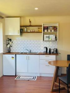 a kitchen with white cabinets and a wooden table at Logies Lodge in Ruakaka