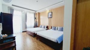 a hotel room with two beds and a desk at Khách sạn Minh Quang in Phan Rang–Tháp Chàm