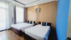 two beds in a room with blue walls at Khách sạn Minh Quang in Phan Rang–Tháp Chàm