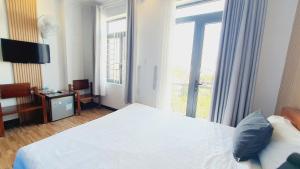 a hotel room with a bed and a large window at Khách sạn Minh Quang in Phan Rang–Tháp Chàm
