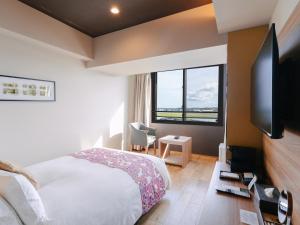 a bedroom with a bed and a large window at Senagajima Island Resort & Spa in Tomigusuku