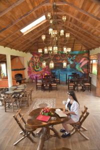 a woman sitting at a table in a restaurant at Las Orquídeas Runtun Lodge in Baños