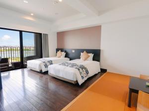 two beds in a room with a balcony at Senagajima Island Resort & Spa in Tomigusuku +241 photos