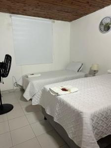 two beds in a white room with a window at Casa Cortijos in Valledupar