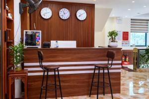 a bar with three clocks on the wall and two stools at SanTran Hotel and Spa in Hai Phong