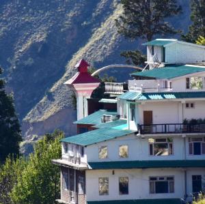 a large white building with a green roof at Hotel Buro The Gate in Kalpa