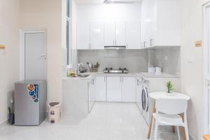 a white kitchen with a refrigerator and a table at Deam Stay in Kulhudhuffushi