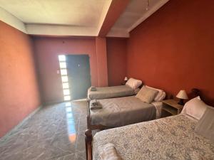 a room with three beds in a room with orange walls at Casa Alfonso 4 huéspedes y cochera gratis in Humahuaca