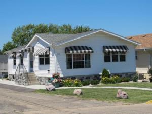a white house with black an awnings on it at Black Hawk Motel & Suites in Wisconsin Dells
