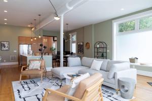 a living room with a white couch and a kitchen at Gorgeous 5BR Storefront Home ABODEbucks in Soulard