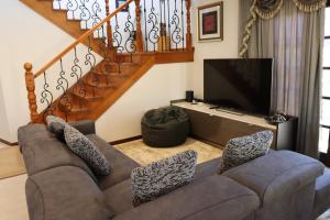 a living room with a couch and a television at Midby's Elegant Guesthouse - 2 En-suite Rooms & 2 Rooms with Shared Bathroom in Perth