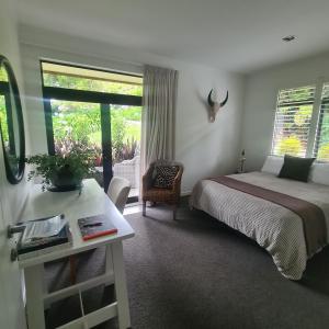 a bedroom with a bed and a table and a window at Sandspit Hideaway in Sandspit