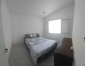 a white bedroom with a bed and a window at Casa playera 2 dormitorios in La Paloma