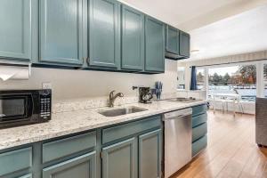 a kitchen with blue cabinets and a sink and a microwave at Riverside Cottage - Just Steps from the Deschutes in Bend