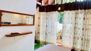 a bedroom with a window with curtains and a mirror at Bliss Cottage in Gampola