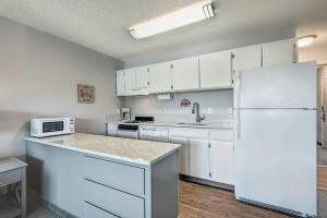 a kitchen with white cabinets and a white refrigerator at Downtown Condo with Riverview & Balcony in Bend