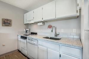 a kitchen with white cabinets and a sink at Downtown Condo with Riverview & Balcony in Bend
