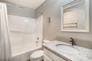 a white bathroom with a sink and a toilet at Downtown Condo with Riverview & Balcony in Bend