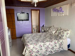 a bedroom with a bed and a tv on the wall at Cobertura luxuosa Marambaia in Barra de Guaratiba