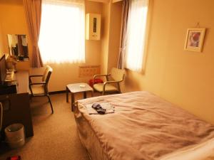 a bedroom with a bed and chairs and a window at Hotel Heart Inn in Hakodate