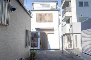 a white house with a wooden door in a alley at 三十三 和華waka in Kyoto