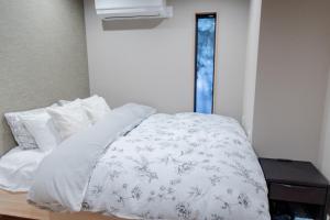 a bed with a white comforter and pillows at 三十三 和華waka in Kyoto
