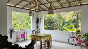 a dining room with a table and two windows at HideWay Guest House Midigama in Midigama East
