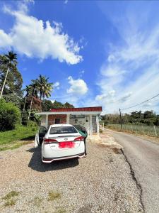 a white car parked in front of a garage at IdaSari Guest House Bukit Bunga in Kampong Bukit Bunga