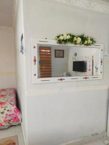 a mirror on a wall with flowers on it at IdaSari Guest House Bukit Bunga in Kampong Bukit Bunga